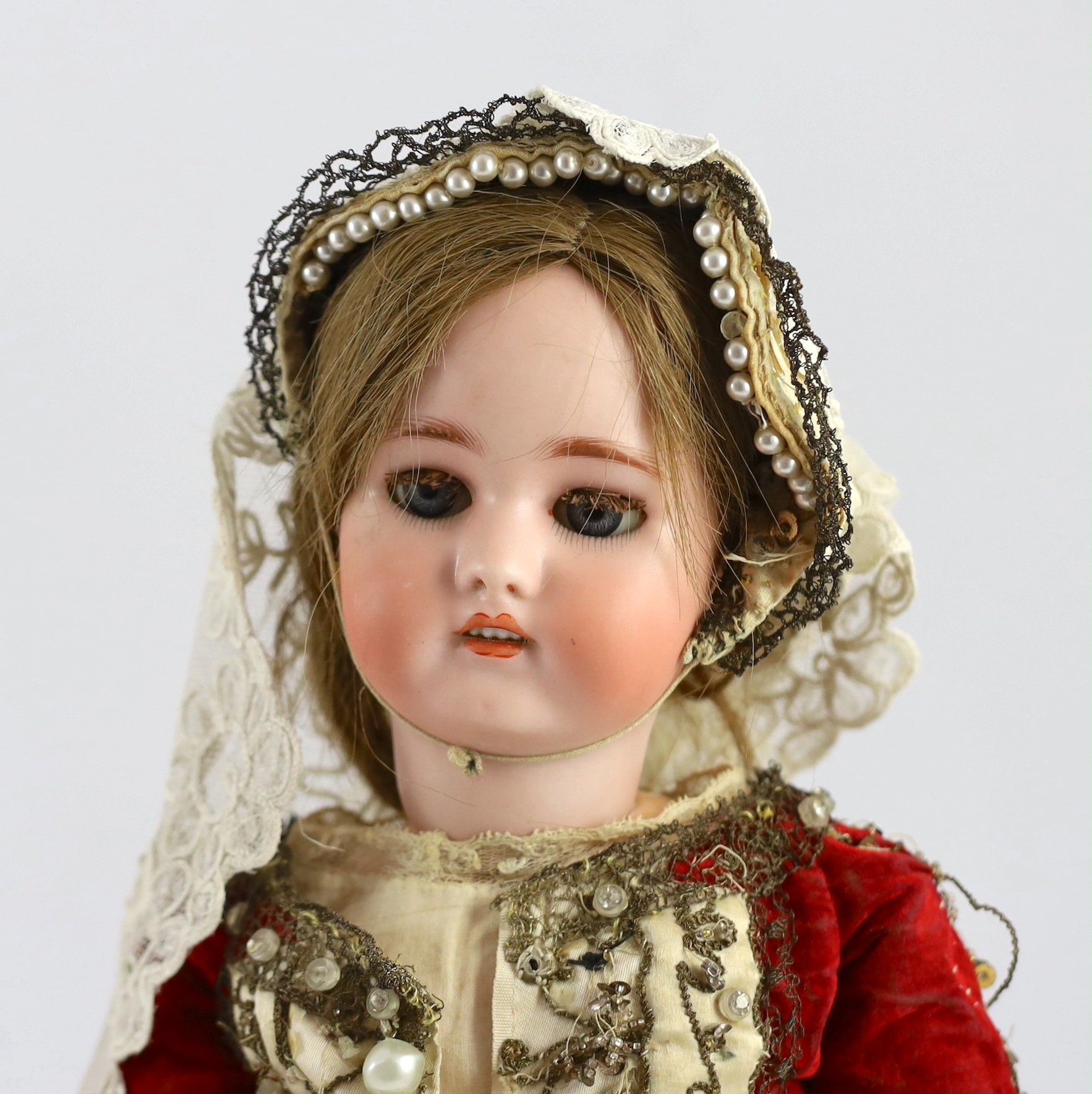 A Simon & Halbig bisque doll, mould 1078, sleeping eyes and open mouth, jointed wood and composition body, sequinned cream and red velvet dress, 19in.